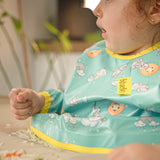 Gros plan détaillé sur les motifs et la matière du bavoir de rechange bleu-vert. | Detailed close-up of the blue-green replacement bib pattern and fabric.